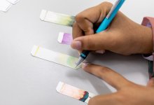 A photo of a student taking notes of four ink chromatography results.