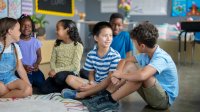 Elementary students sitting and talking on the floor