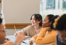 A photo of high schoolers discussing in small groups.