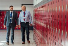 A photo of a teacher and principal in a discussion while walking through a school hallway.