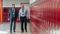 A photo of a teacher and principal in a discussion while walking through a school hallway.