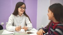 A photo of two elementary students engaged in a discussion at their desks.