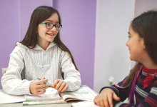 A photo of two elementary students engaged in a discussion at their desks.