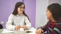 A photo of two elementary students engaged in a discussion at their desks.