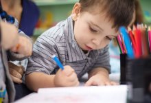 A photo of a group of preschoolers enthusiastically writing using colored pencils.