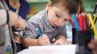 A photo of a group of preschoolers enthusiastically writing using colored pencils.