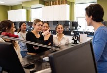 A photo of a small group of high school physics students asking their teacher questions.
