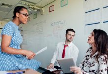 A photo of three teachers having a serious discussion in a classroom.