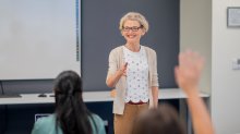 A substitute teacher in the front of a classroom talking to students