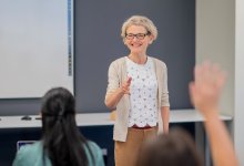 A substitute teacher in the front of a classroom talking to students