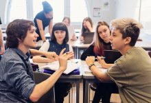 A photo of a small group of middle school students having a discussion while working on a writing assignment.