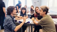 A photo of a small group of middle school students having a discussion while working on a writing assignment.