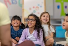 A photo of kindergarten students smiling while repeating after their teacher, representing teaching positive self-talk