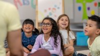 A photo of kindergarten students smiling while repeating after their teacher, representing teaching positive self-talk