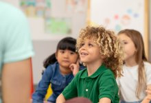 A photo of preschool students listening attentively to their teacher during circle time.