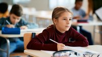 Elementary student taking notes at desk