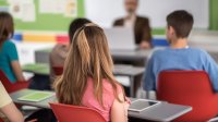 A photo focused on a female middle school student sitting amongst her classmates during a lesson.