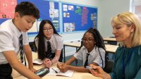 A photo of a teacher working with a small group of middle school students.