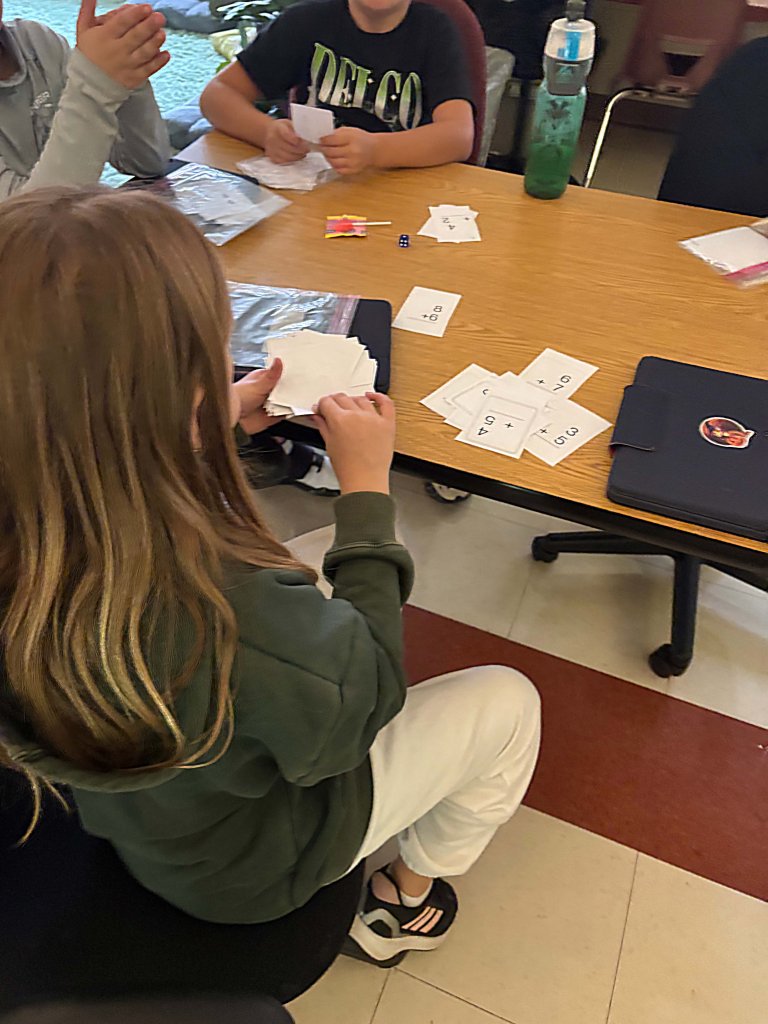 A photo of three students playing a math-based card game.