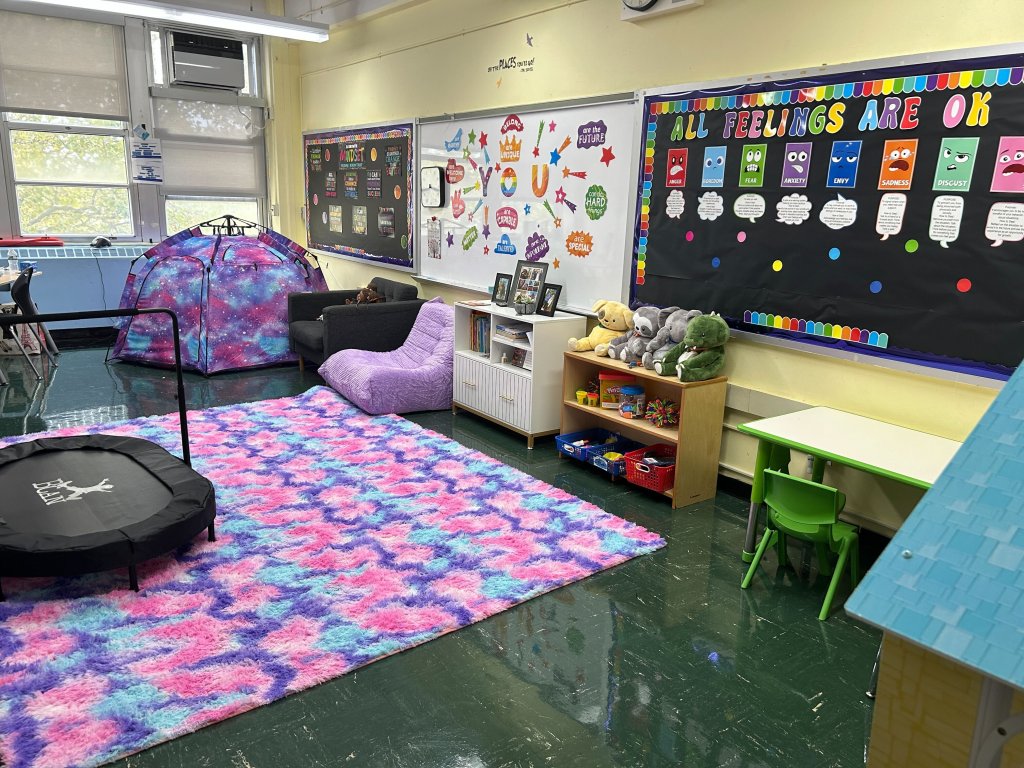 Photo of a classroom with a bulletin board that says "All Feelings Are OK"