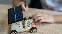 A photo of a student working on building a small wooden car powered by a solar panel, representing the topic of middle school STEM projects