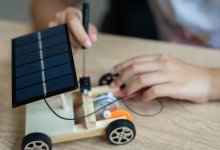 A photo of a student working on building a small wooden car powered by a solar panel, representing the topic of middle school STEM projects