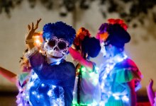 Participants in a Day of the Dead parade wave to the crowd in San Antonio, Texas