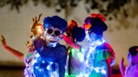 Participants in a Day of the Dead parade wave to the crowd in San Antonio, Texas