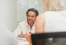 A photo of a meeting between three people.