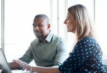 Two coworkers reviewing information on a laptop together