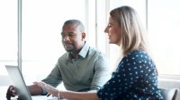 Two coworkers reviewing information on a laptop together