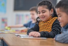 Elementary students reading a book together
