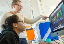 A photo of two middle school students editing footage of them in front of a green screen.