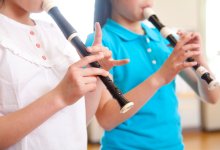 A photo of two young students playing on the recorder.