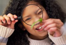 Child looking at leaf with a magnifying glass