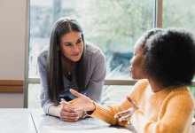 A photo of a high school student having a one-on-one conversation with a teacher.