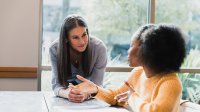 A photo of a high school student having a one-on-one conversation with a teacher.