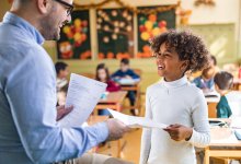 A photo of an elementary student submitting an exit ticket to their teacher.