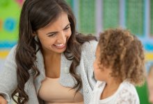 A photo of a preschool teacher calmly talking to one of their students.