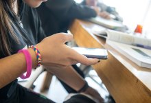 A photo of a middle school student using a cell phone at their desk.