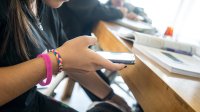 A photo of a middle school student using a cell phone at their desk.