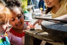 A photo of two preschool students outside excitedly looking at a spider.