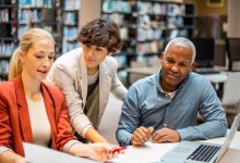 A photo of a small group of staff having a meeting in a library.