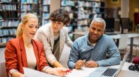 A photo of a small group of staff having a meeting in a library.
