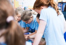 A photo of a small group of elementary students working on math problems using tablets.