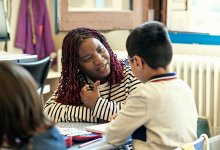 A photo of a teacher kneeling down to have a discussion with an elementary student.