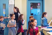 Elementary teacher welcoming students as they walk into class