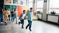 A photo of elementary students walking in a straight line over the long crack in between the tiles on the floor.