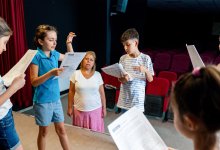 A photo of elementary students rehearsing a skit in their school auditorium.