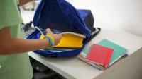 Student putting notebooks in backpack
